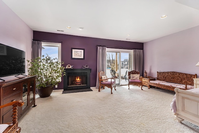 living room featuring a fireplace with flush hearth, visible vents, carpet flooring, and recessed lighting