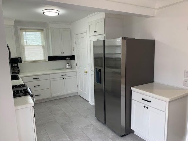 kitchen with range with gas cooktop, white cabinets, light countertops, and stainless steel fridge with ice dispenser