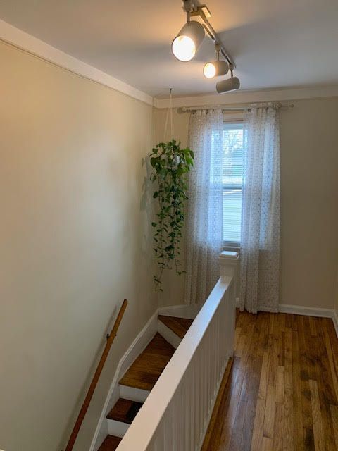 hallway with crown molding, baseboards, dark wood-type flooring, and an upstairs landing