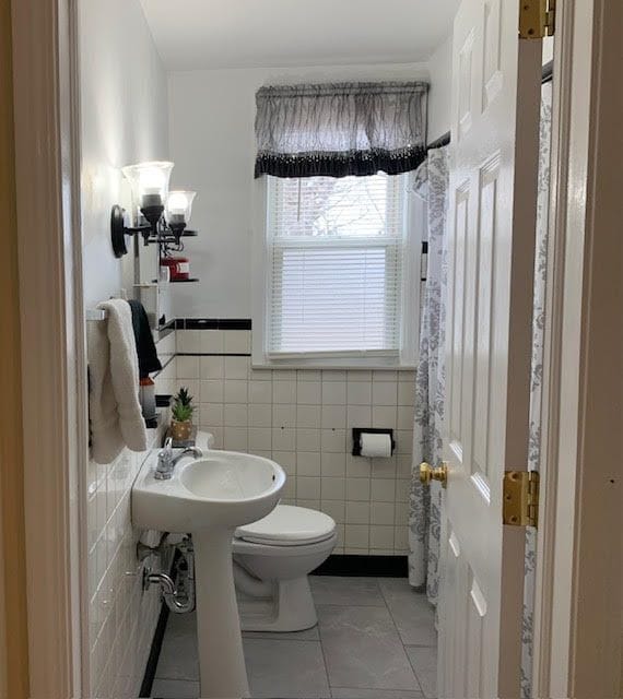 bathroom featuring a wainscoted wall, tile patterned flooring, toilet, and tile walls