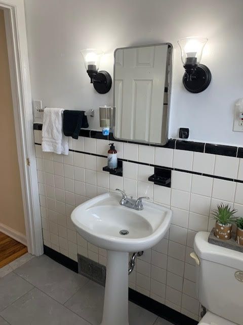 bathroom with toilet, tile patterned flooring, and tile walls