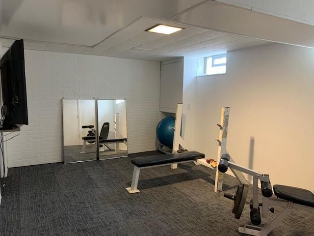 workout room featuring brick wall and dark carpet