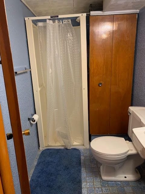 full bath with a stall shower and toilet