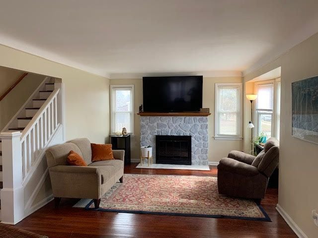 living room with stairway, wood-type flooring, a fireplace, and baseboards