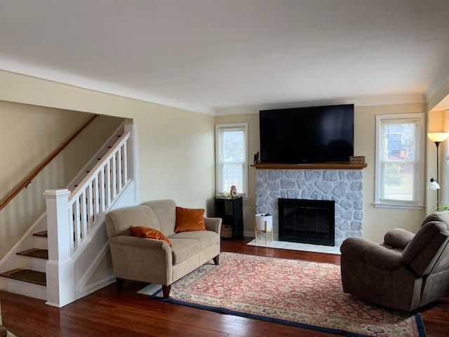 living area featuring stairs, a fireplace, and wood finished floors