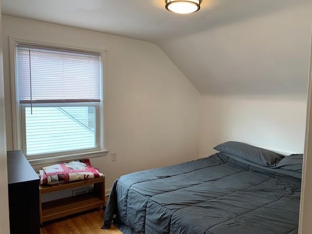 bedroom with lofted ceiling and wood finished floors