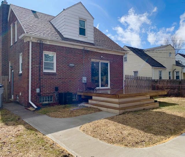 rear view of house featuring a deck, central AC unit, brick siding, a shingled roof, and fence