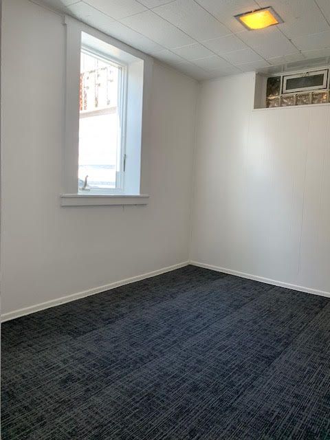 unfurnished room with baseboards and dark colored carpet