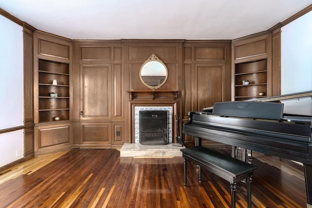 unfurnished room with dark wood-style floors, a fireplace with raised hearth, and built in shelves