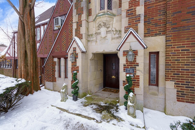 snow covered property entrance with brick siding