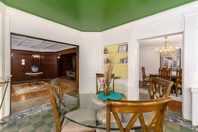 dining room with a chandelier, ornamental molding, and a decorative wall