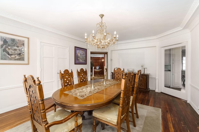 dining area with an inviting chandelier, ornamental molding, a decorative wall, and wood finished floors