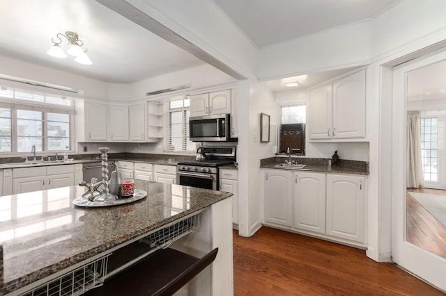 kitchen with a sink, stainless steel appliances, dark stone countertops, and open shelves