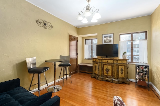 living room with baseboards, a chandelier, wood finished floors, and a textured wall