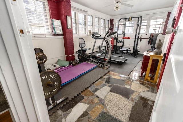 exercise area with ceiling fan and stone finish floor