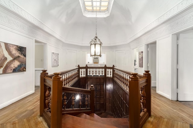 corridor featuring hardwood / wood-style flooring, baseboards, ornamental molding, and an upstairs landing