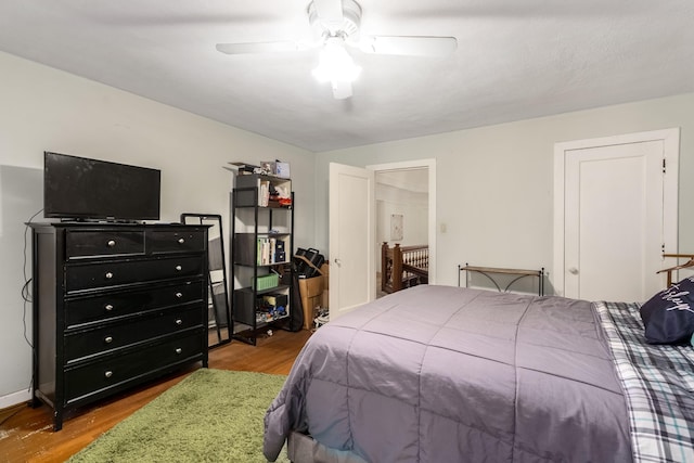 bedroom with ceiling fan, wood finished floors, and baseboards