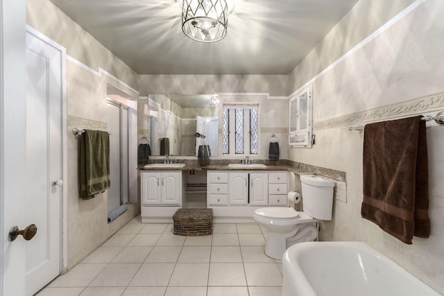 bathroom featuring tile walls, toilet, a stall shower, vanity, and tile patterned flooring