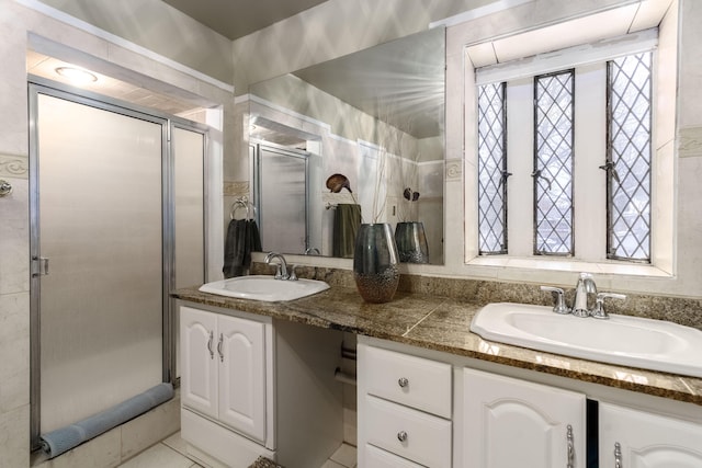 full bathroom with double vanity, a shower stall, and a sink