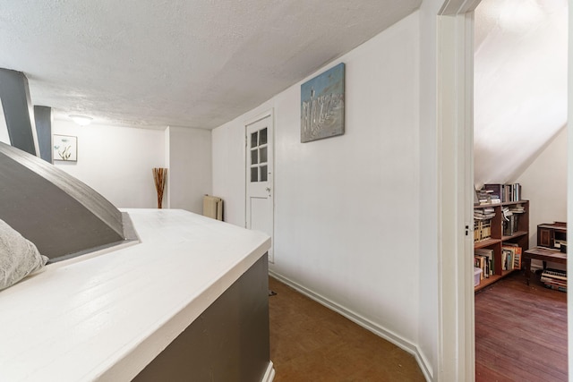 office featuring a textured ceiling, dark wood-type flooring, baseboards, and radiator