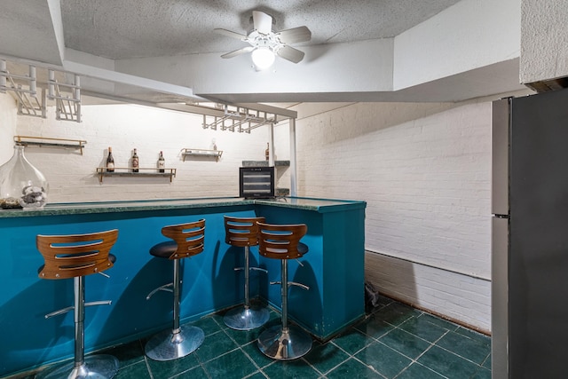 bar with dark tile patterned flooring, brick wall, indoor bar, and freestanding refrigerator