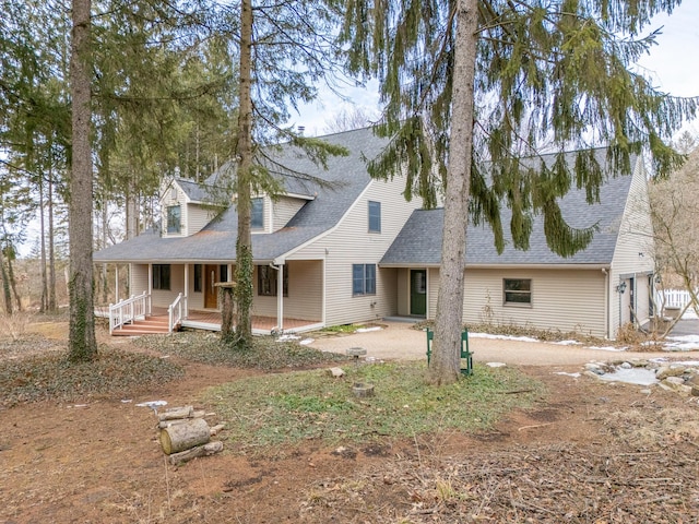 view of front of home featuring driveway, a porch, and a shingled roof