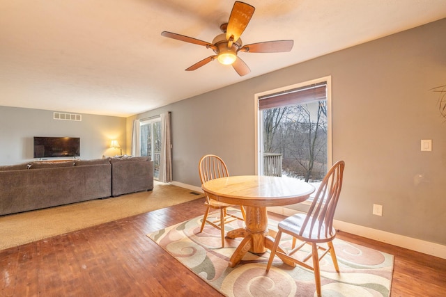 dining space with hardwood / wood-style floors, a ceiling fan, visible vents, and baseboards