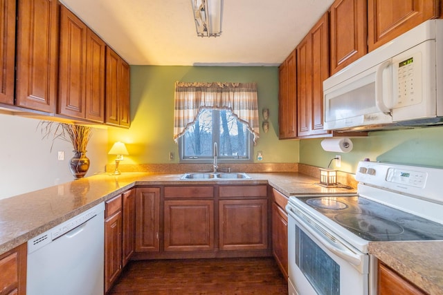 kitchen with light countertops, white appliances, brown cabinets, and a sink