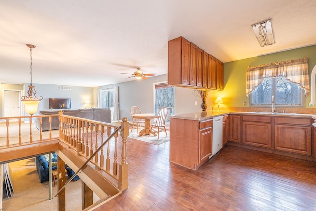 kitchen featuring white dishwasher, visible vents, a sink, and wood finished floors