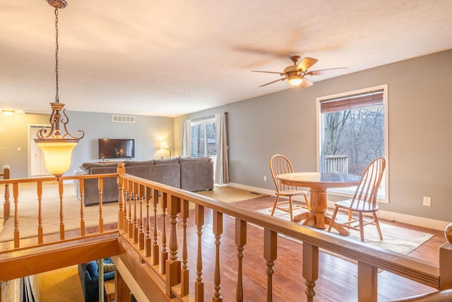 staircase featuring a ceiling fan, baseboards, visible vents, and wood finished floors