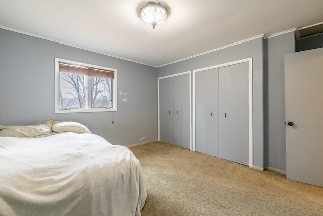 bedroom with carpet floors, baseboards, ornamental molding, and two closets