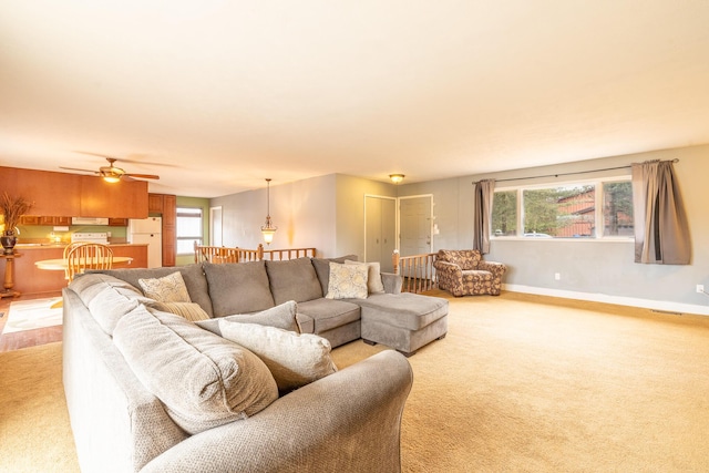 living area featuring a ceiling fan, light carpet, and baseboards