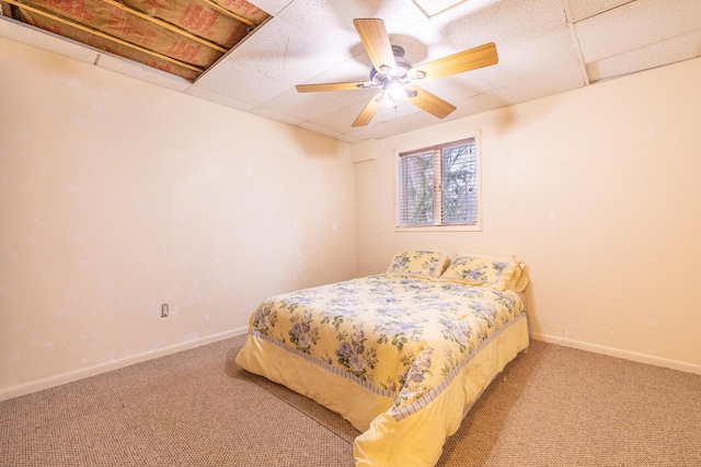 carpeted bedroom with a ceiling fan, a paneled ceiling, and baseboards