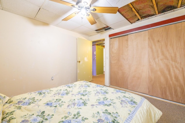 bedroom featuring visible vents, a drop ceiling, a ceiling fan, carpet, and a closet