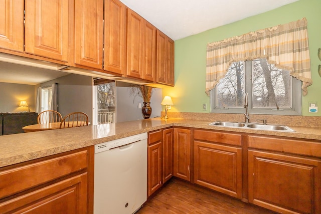 kitchen with a sink, brown cabinets, light countertops, and dishwasher