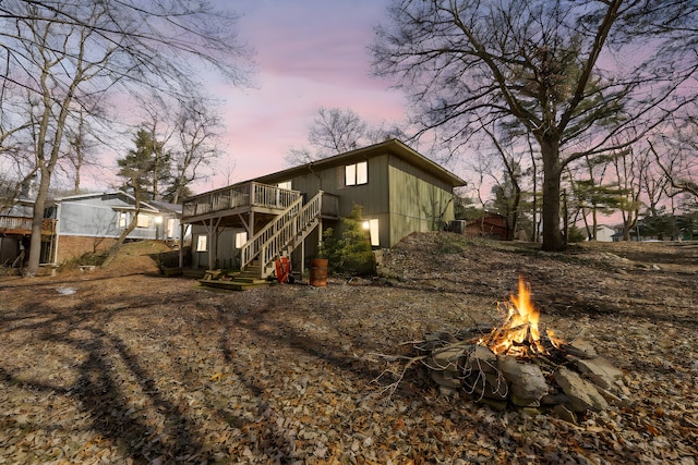 back of house with a fire pit, a wooden deck, and stairs