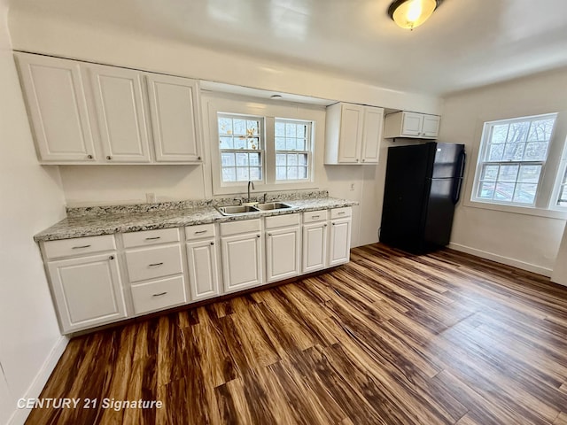 kitchen featuring dark wood finished floors, freestanding refrigerator, white cabinets, a sink, and plenty of natural light