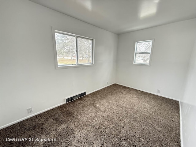 spare room featuring carpet floors, baseboards, and visible vents