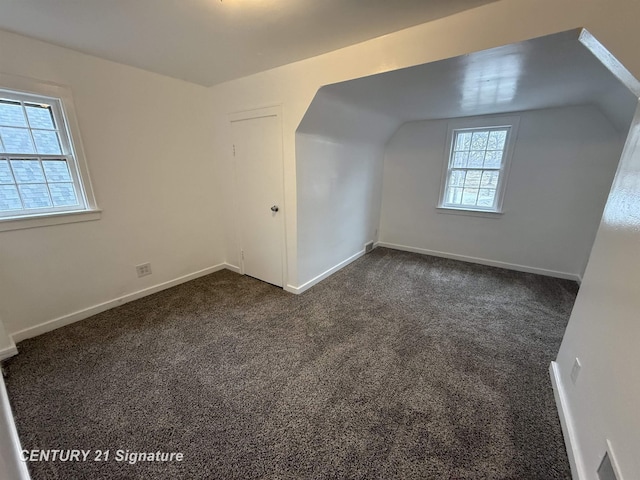 bonus room with dark colored carpet, vaulted ceiling, and baseboards