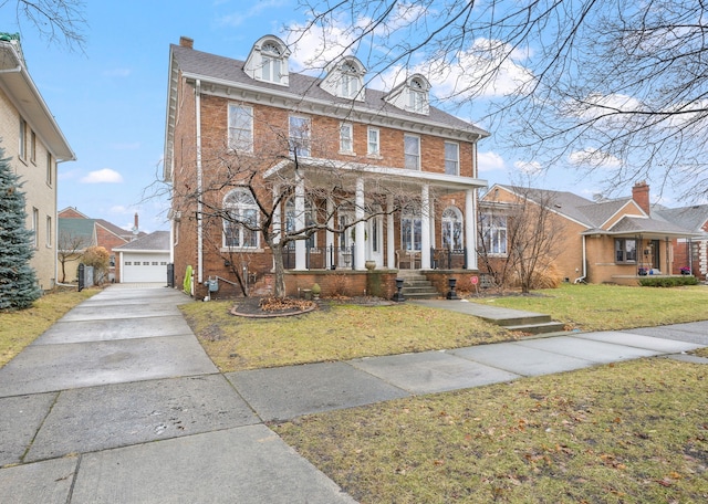 view of front of home with covered porch, an outbuilding, a front lawn, and brick siding