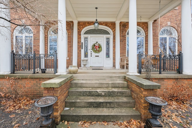 doorway to property with a porch and brick siding