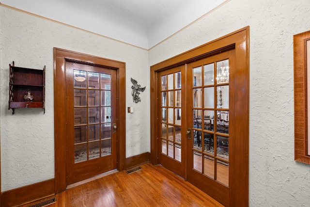 doorway featuring visible vents, french doors, hardwood / wood-style floors, and a textured wall