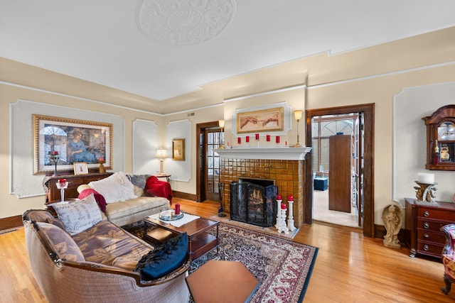 living room featuring a fireplace, baseboards, and wood finished floors