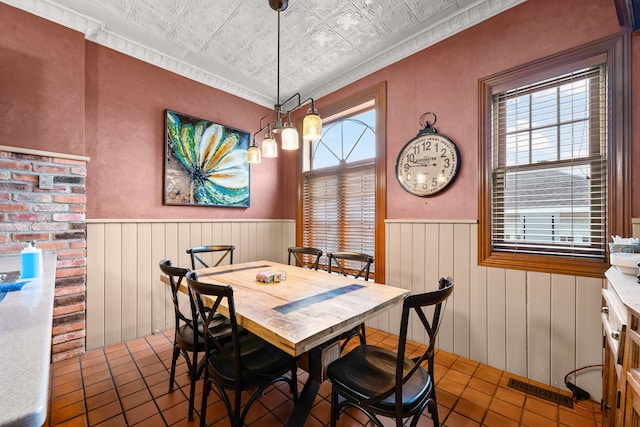 dining space with an ornate ceiling, a wainscoted wall, wood walls, and visible vents