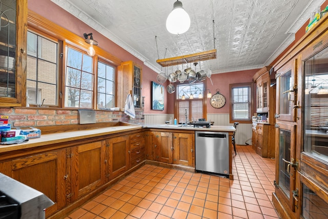 kitchen with a wainscoted wall, a sink, brown cabinets, dishwasher, and an ornate ceiling