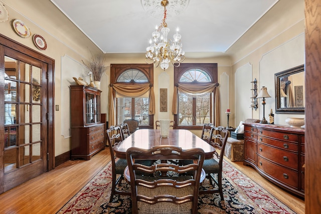 dining space featuring a notable chandelier, light wood-style flooring, and baseboards