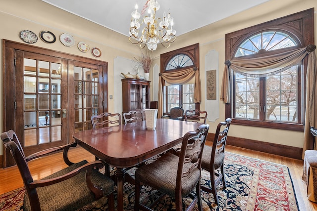 dining room with baseboards, wood finished floors, and an inviting chandelier