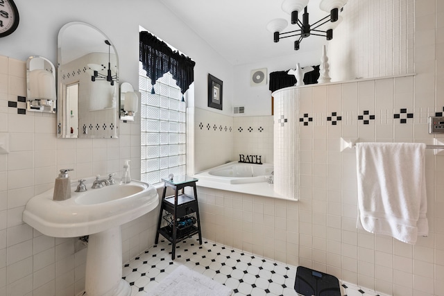 bathroom with tile patterned flooring, a garden tub, and tile walls