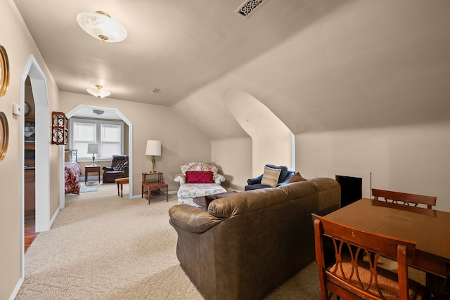 living area with arched walkways, light colored carpet, visible vents, vaulted ceiling, and baseboards