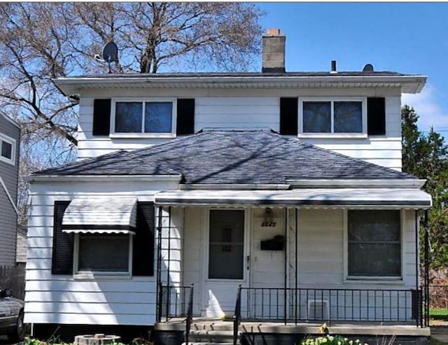 american foursquare style home featuring covered porch, roof with shingles, and a chimney